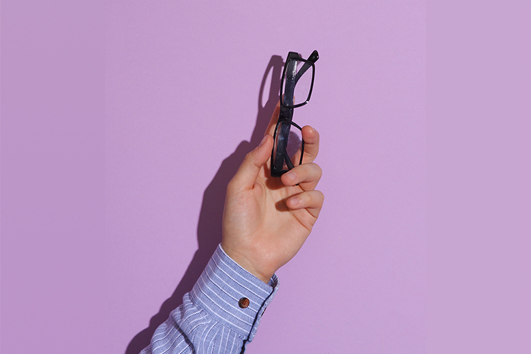 eine ausgestreckte Hand hält eine Brille