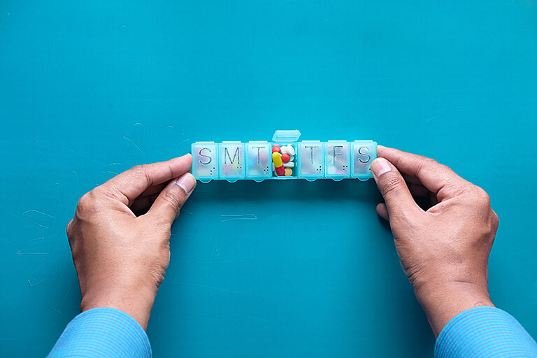 Hände halten eine Pillenbox