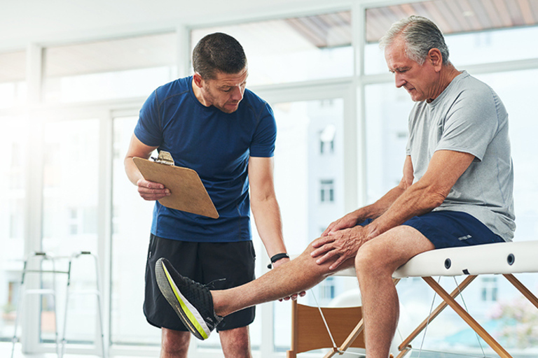 Physiotherapeut zeigt einem Mann eine Bewegung